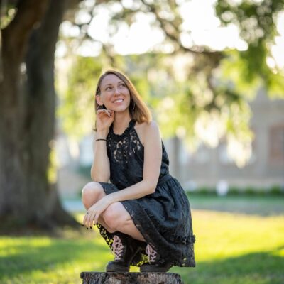 A woman in black dress sitting on a stump