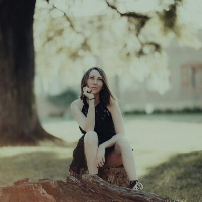 A woman sitting on a tree stump in front of a tree
